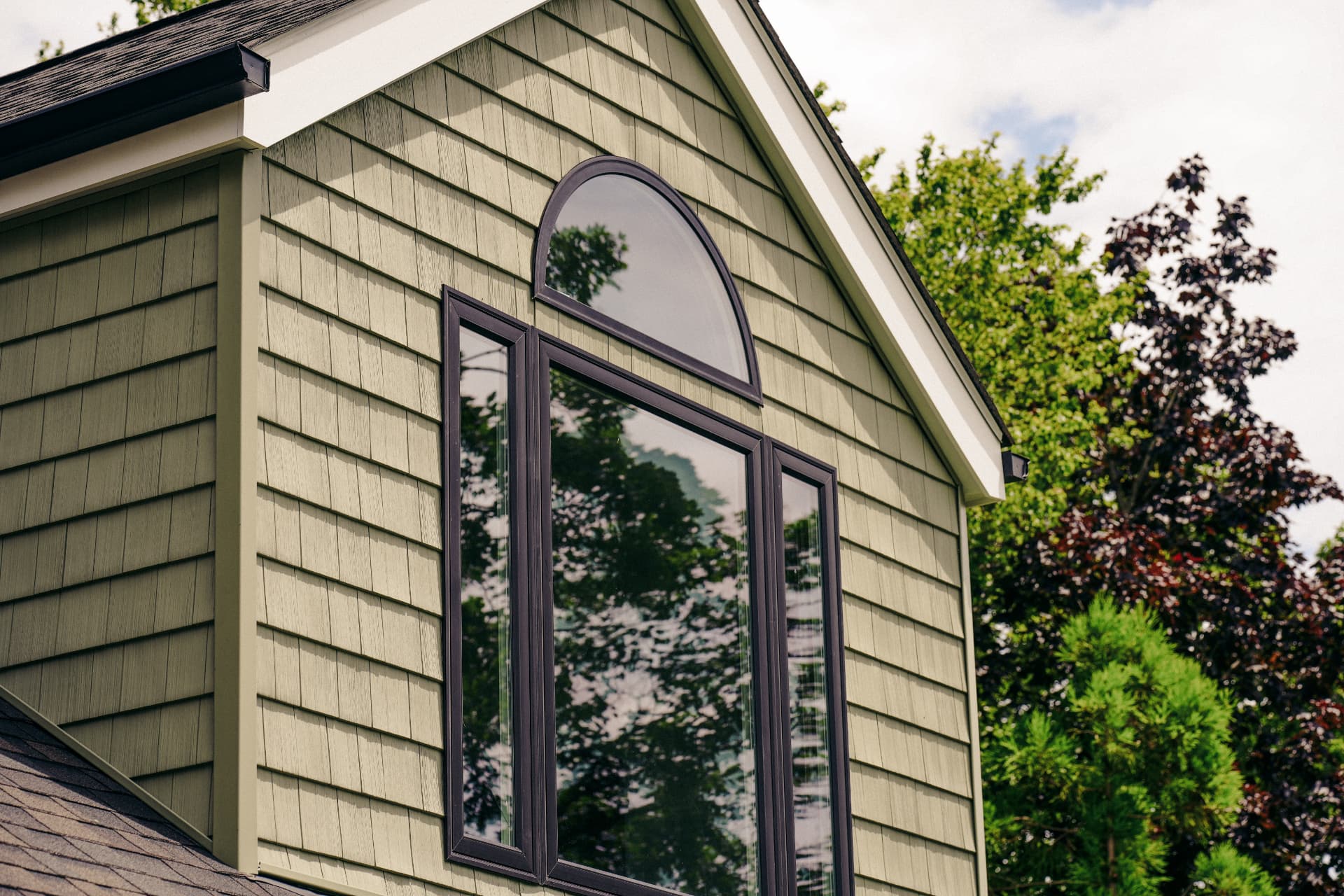 New dark-framed windows with an arched transom on a home with shake siding