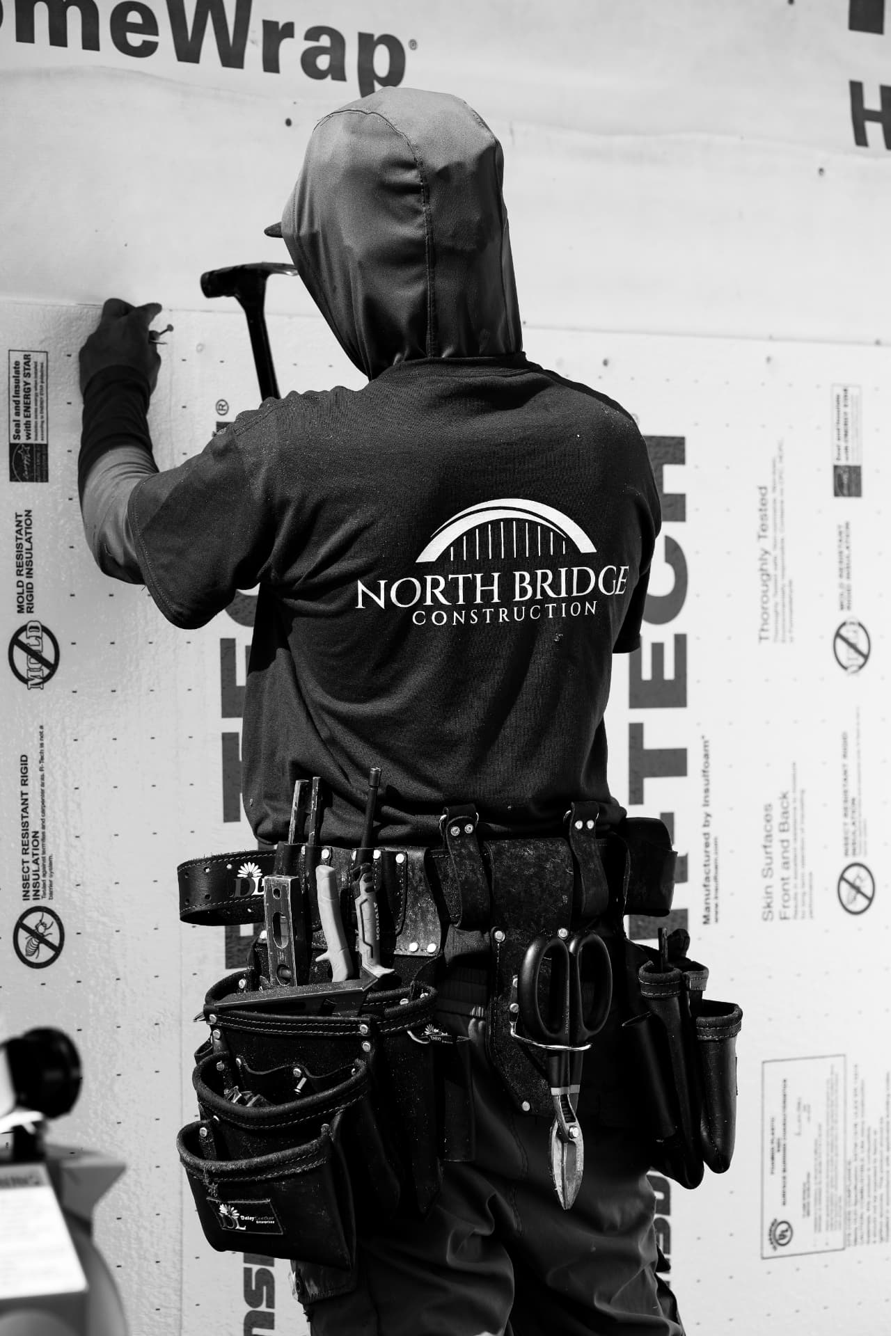 North Bridge Construction team member in a branded shirt wrapping a wall in insulation