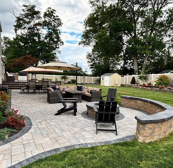 Paver patio with a curved stone sitting wall and a fire table
