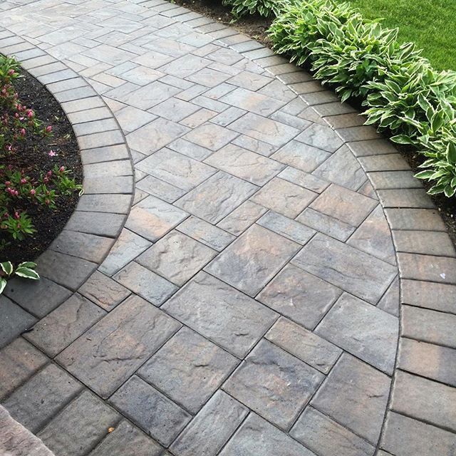 Paver walkway built by North Bridge Construction curving past mulched planting beds and hostas to a home's entrance