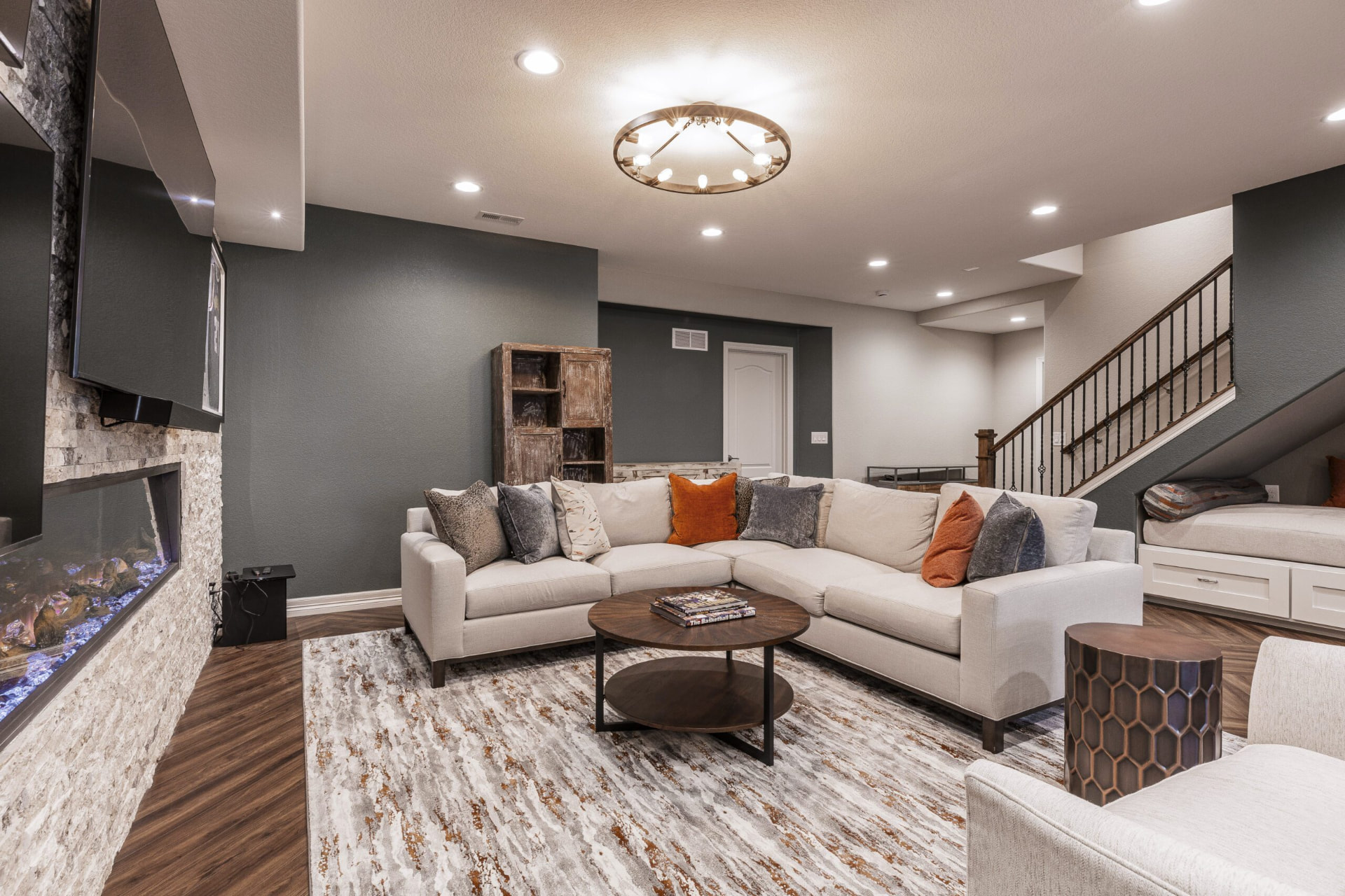 Finished basement lounge with a stone fireplace and cream sectional sofa